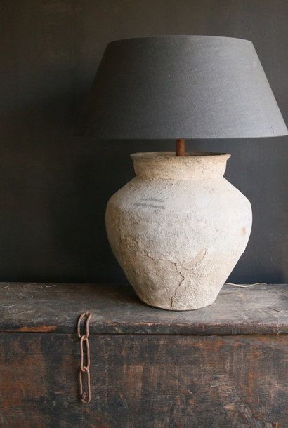 a large white vase sitting on top of a wooden table next to a black lamp