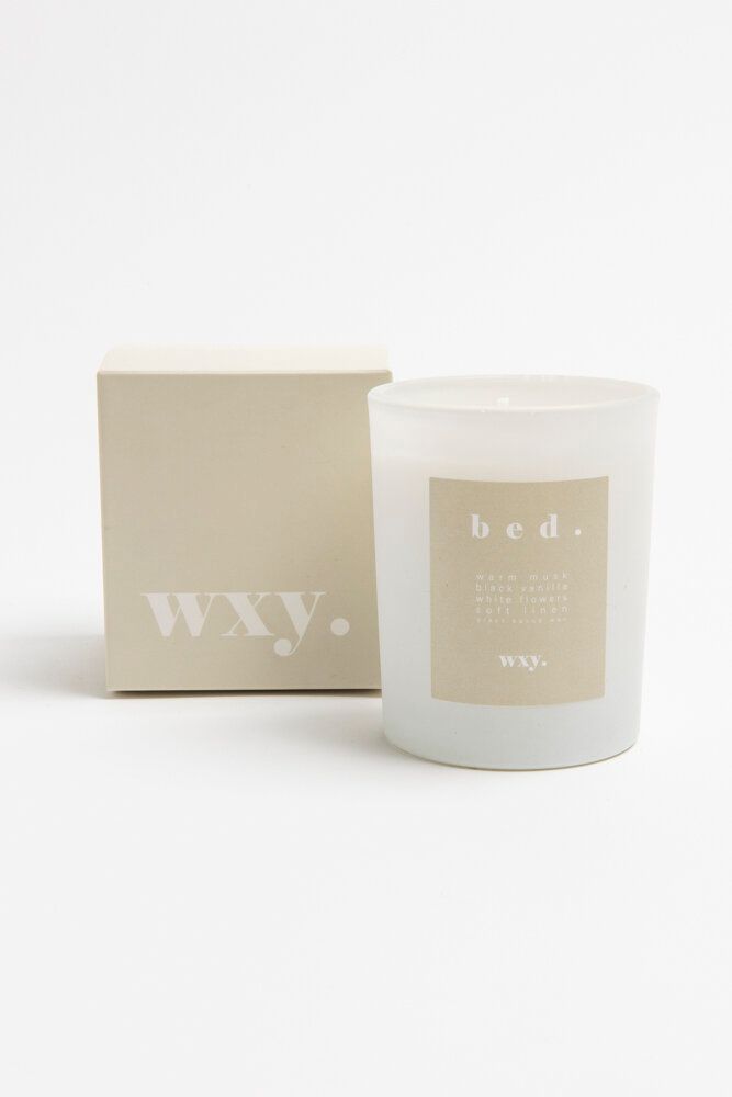 a white candle next to a box on a white surface with the word wvw printed on it