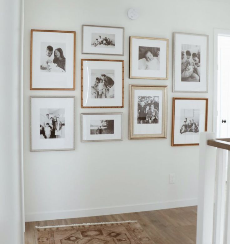 a wall with many pictures on it and a rug in front of the door way