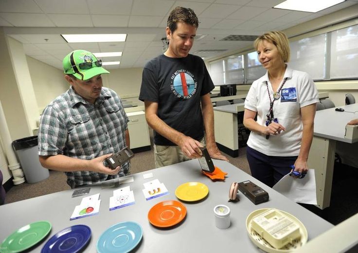 three people standing around a table with plates on it