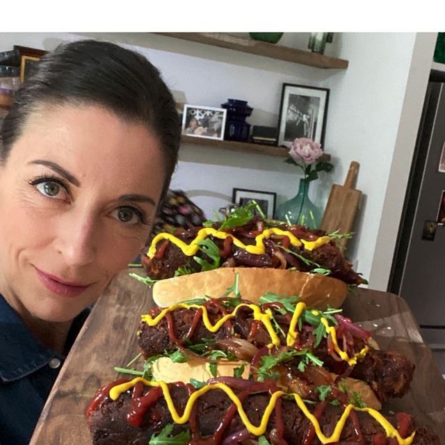 a woman holding up a large tray with two hot dogs on buns covered in ketchup and mustard