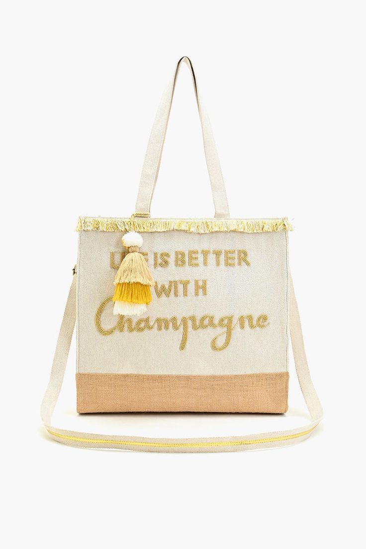 Hand Beaded Tote Hand Beaded 'Life Is Better with Champagne' Saying on It in Gold Fully Lined Interior with Zip Pocket Off-White Handwoven Jacquard Backing with Silver Lurex Detail Made In Combination with Jute Double Shoulder Straps with Lace Detail Fringed Lace Detail at the Top Magnetic Button Closure Size : 15" X 14" X 6" Step into a summer state of mind and let your free spirit shine with the Champagne Forever Tote! This hand-beaded jute tote is your perfect companion for all things sunny a Greece Clothing, Uni Bag, Free Spirited Woman, Jute Totes, To Buy List, Embroidered Tote, Spring Clothes, Buy List, Clothing Labels