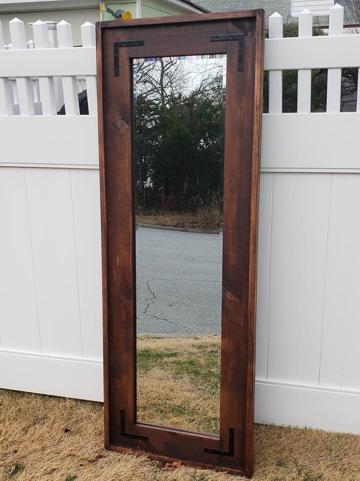 a mirror sitting on the ground in front of a white fence and a wooden door