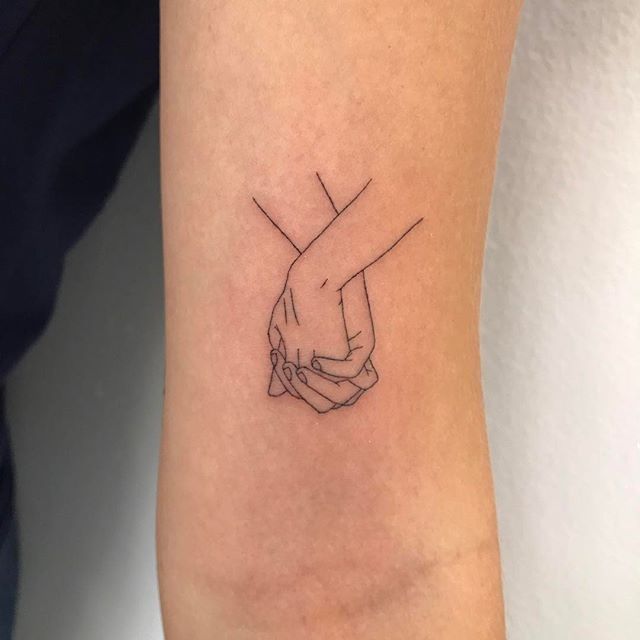 a couple of hands holding each other on the wrist tattoo designs for men and women