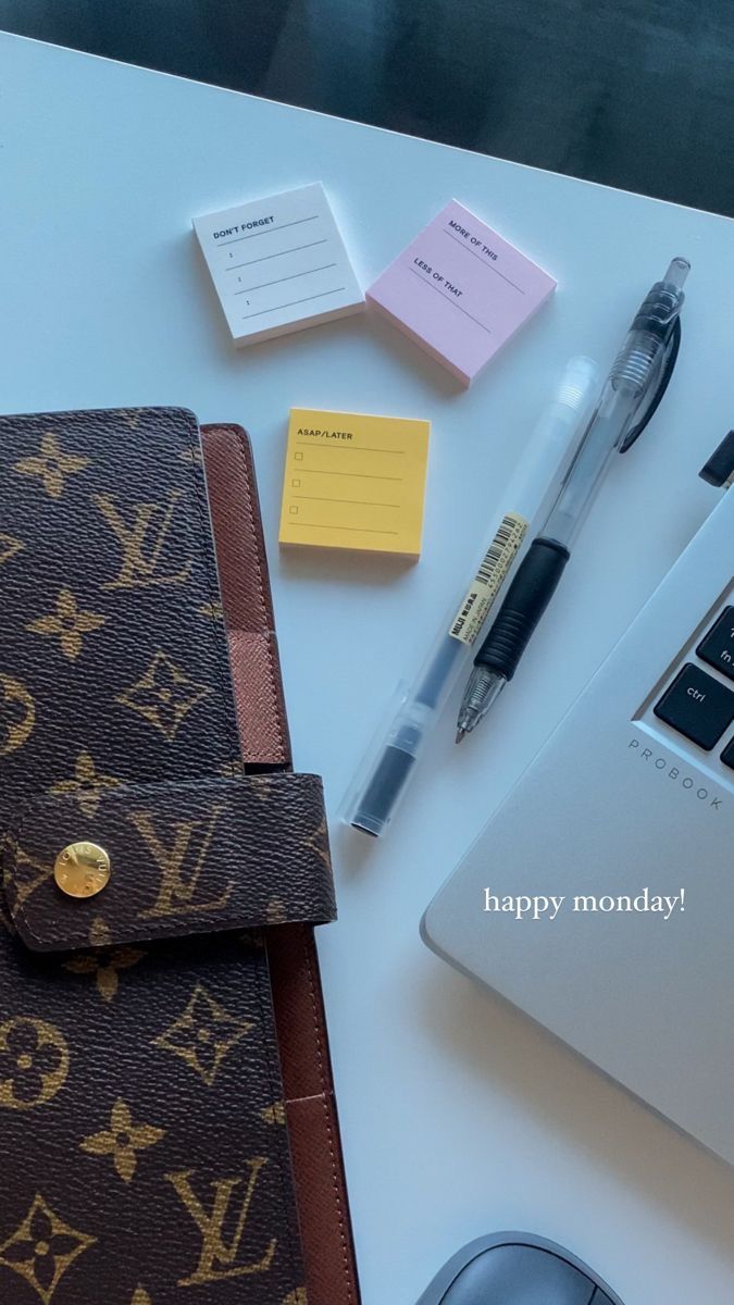 a desk with a laptop, notepad, pen and other office supplies on it