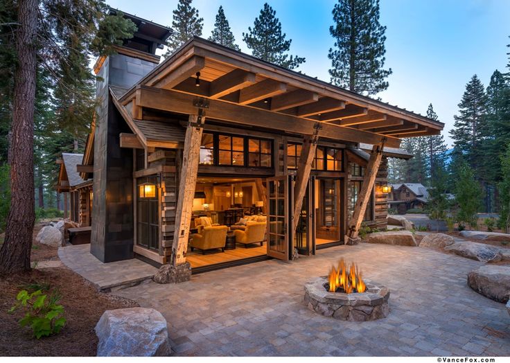 a fire pit in the middle of a stone patio with a wooden structure on top