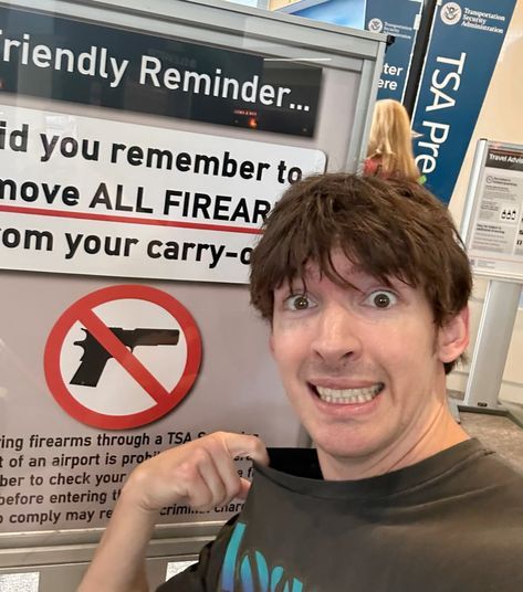 a man holding up a t - shirt in front of a sign that says, if you remember to remove all firebars from your carry on