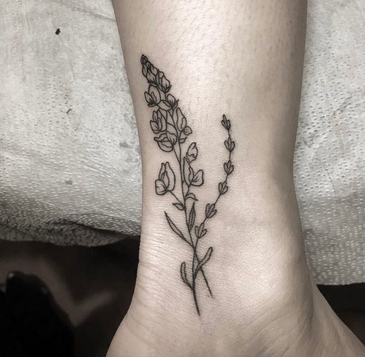 a small flower tattoo on the ankle that is black and white, with flowers growing out of it