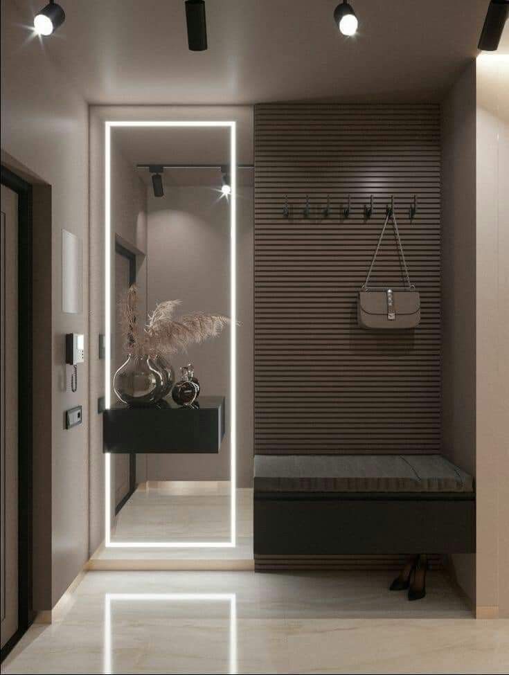 a modern entry way with a bench, mirror and lights on the wall behind it