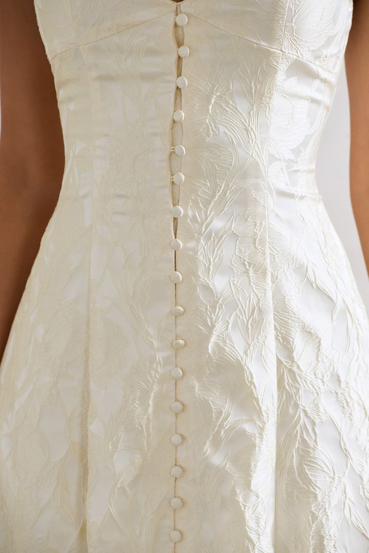 the back of a woman's wedding dress with buttons and beading on it