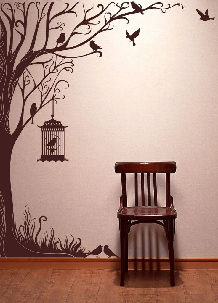 a chair sitting in front of a tree with birds flying around it and a birdcage hanging from the branch