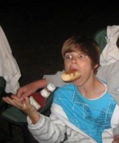 a young man eating a hot dog in his mouth