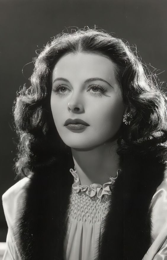 an old black and white photo of a woman wearing a fur stole over her shoulders