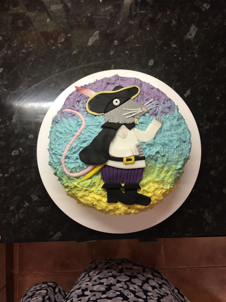 there is a cake that looks like a mouse on the plate and someone's feet are next to it