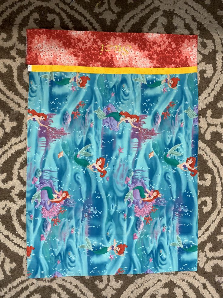 a piece of fabric that is on top of a carpet with an image of fish in the water