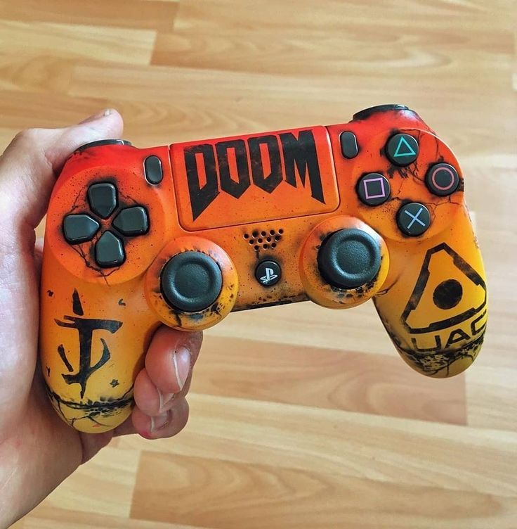 a hand holding an orange and black game controller