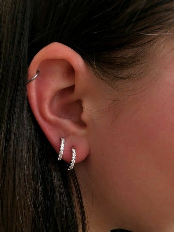 a close up of a woman's ear with two small diamond hoops on it