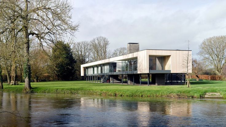 a large house sitting on top of a lush green field next to a body of water