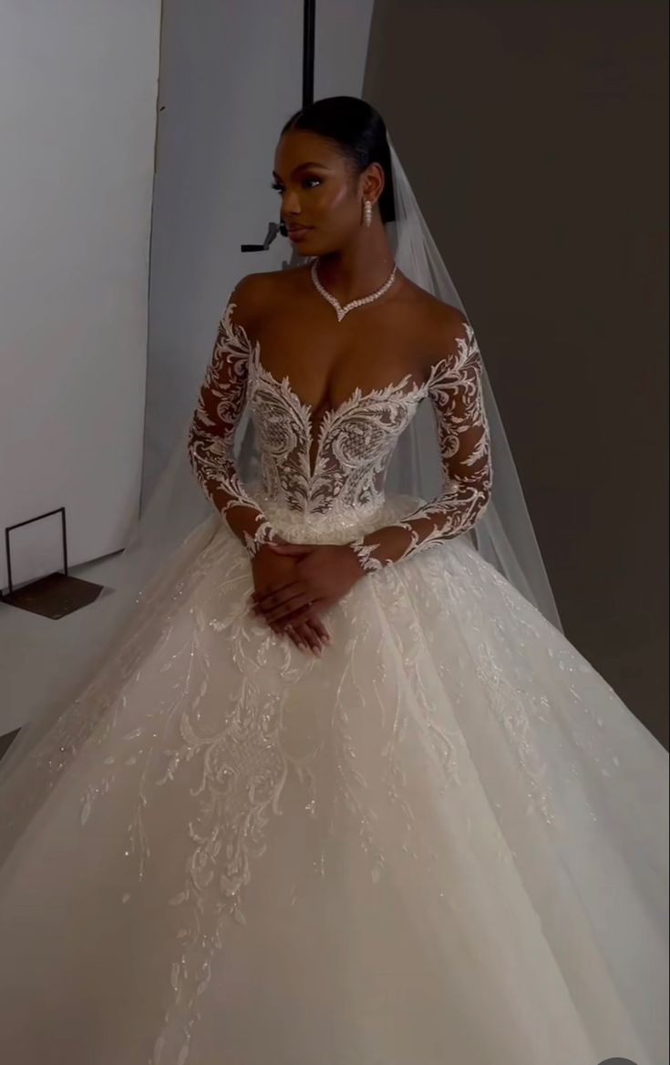 a woman in a wedding dress standing next to a white wall and wearing a tiara