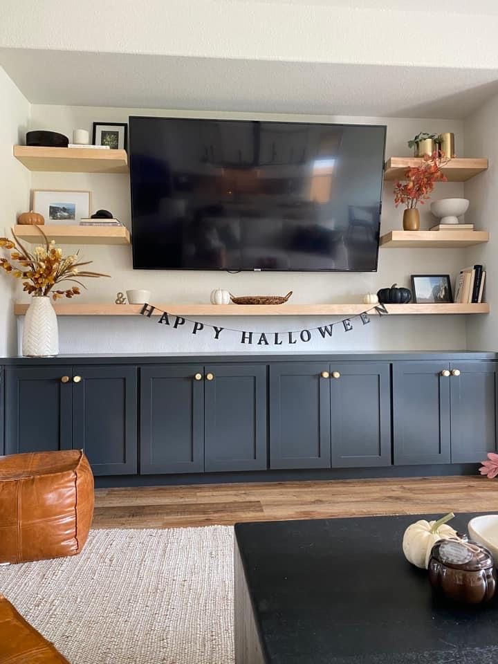 a flat screen tv mounted to the side of a wall in a living room with wooden shelves