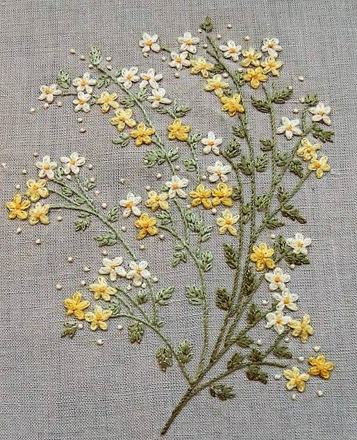 some yellow and white flowers are on a gray surface, with small beads in the middle