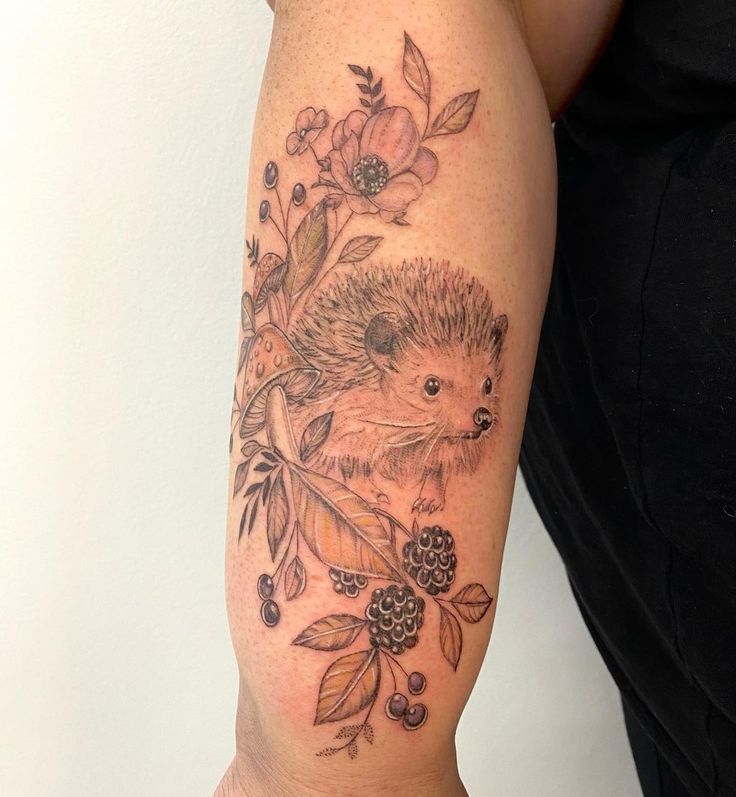 a woman's arm with a hedgehog tattoo on it and flowers in the background