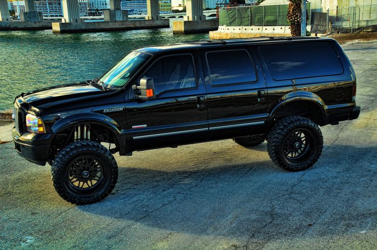 a large black truck parked next to a body of water