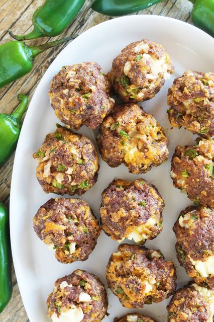 a white plate topped with meatballs covered in cheese and seasoning next to green peppers