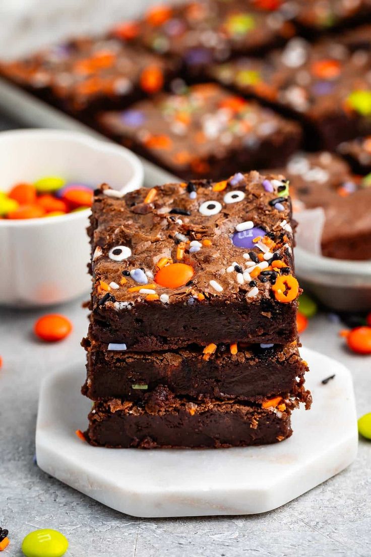 three brownies stacked on top of each other with halloween candies in the background