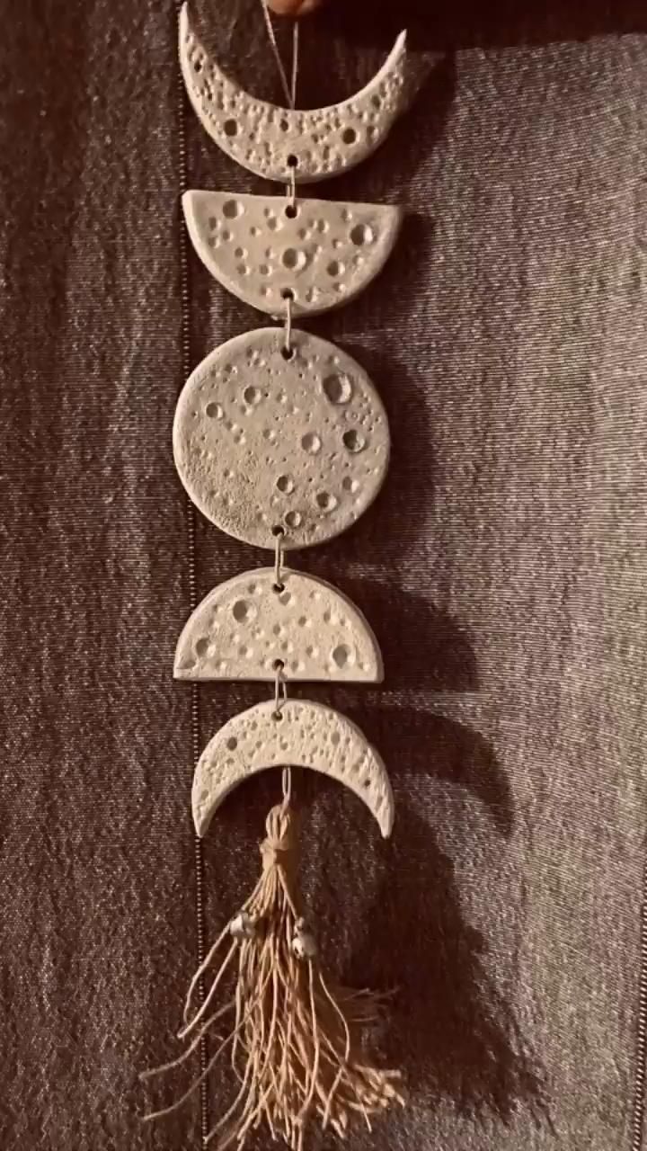 three phases of the moon hanging from a string with some plants growing out of it