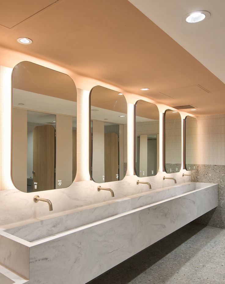 there are four sinks in the bathroom with mirrors on the wall and lights above them