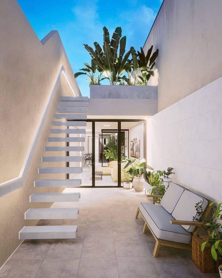 a white staircase leading up to a house with potted plants on either side and two couches in the foreground