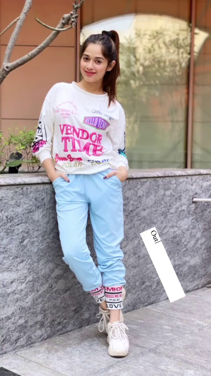 a young woman standing next to a wall