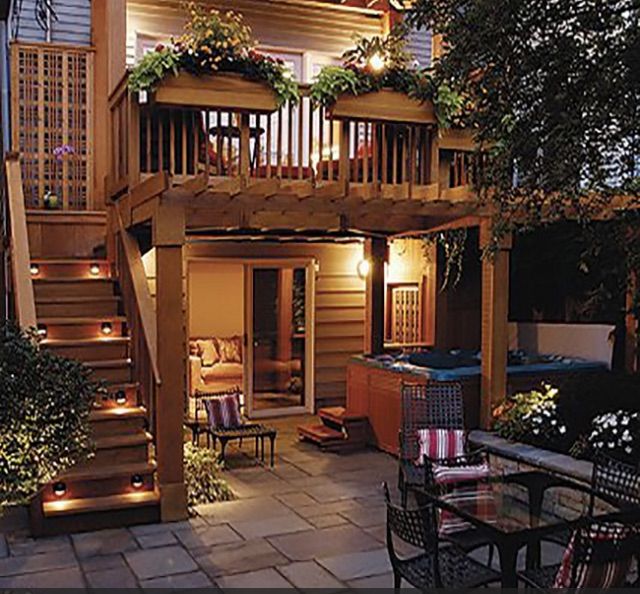 an outdoor patio with stairs, table and chairs at night in front of a house