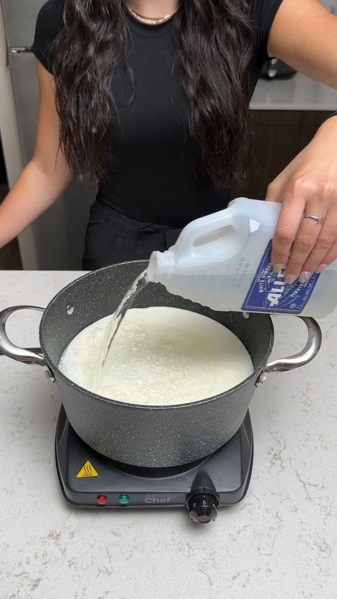 a woman pours milk into a skillet on the stove top while cooking food