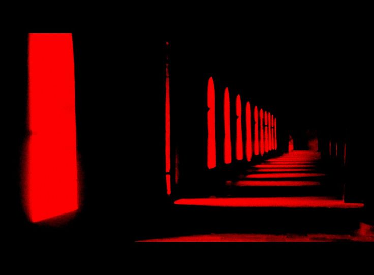 an empty hallway with red lights in the dark