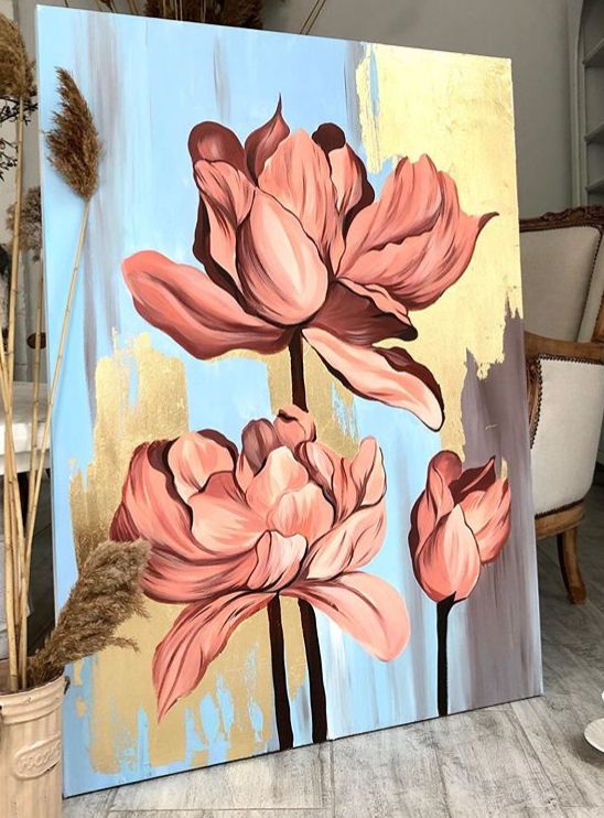 a painting of three pink flowers on a blue and yellow background in a living room