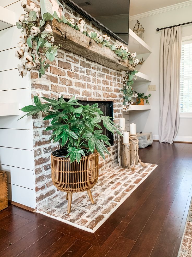 a living room with a brick fireplace and potted plant on the mantle in front of it