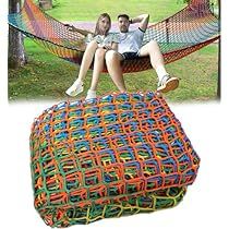 two people sitting on a hammock in the grass and one is holding a book