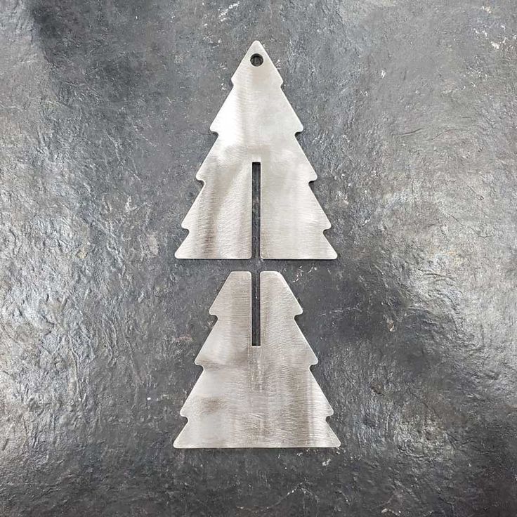 three metal christmas trees sitting on top of a black surface with one cut out to look like it's upside down