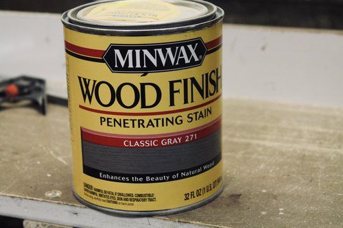 a can of wood finishing stain sitting on top of a table next to a pair of pliers