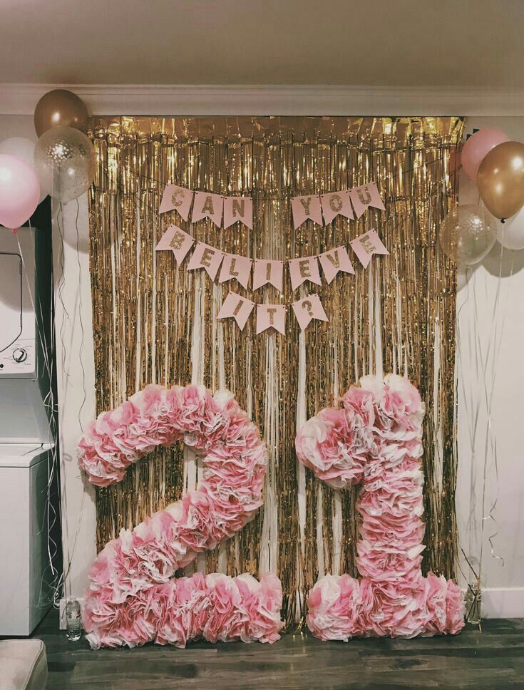 the number twenty two is made out of pink tissue paper flowers and streamers with balloons in the background