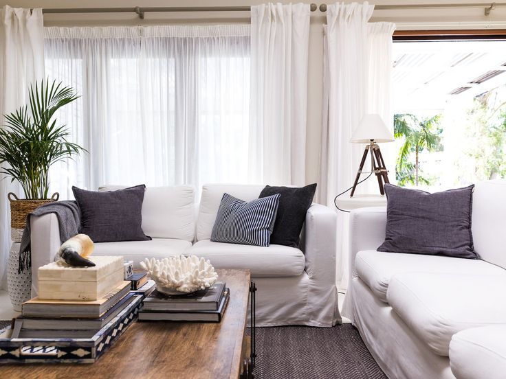 a living room filled with furniture and books on top of a wooden table in front of a window