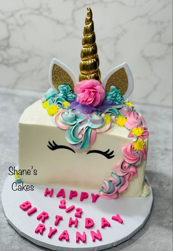 a birthday cake decorated with an unicorn's head and flowers