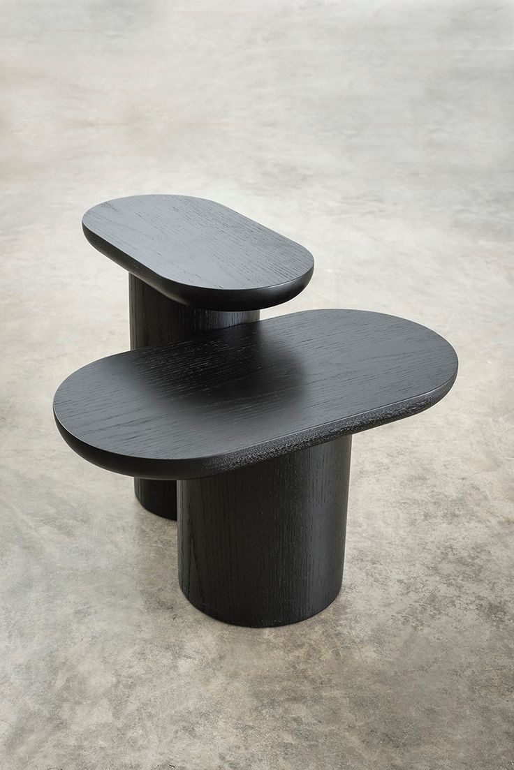 two black tables sitting on top of each other in front of a cement flooring area