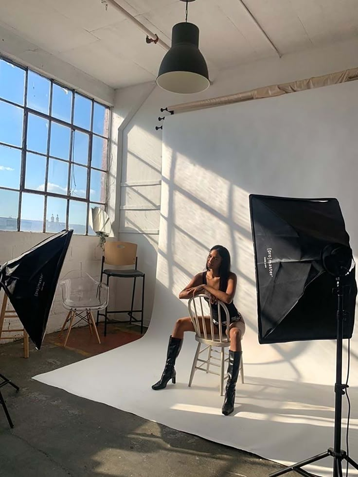 a woman sitting on a chair in front of a camera set up for a photo shoot