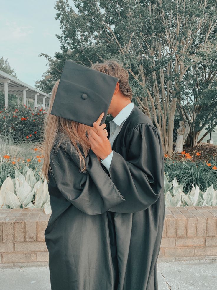 two people in graduation gowns hugging each other