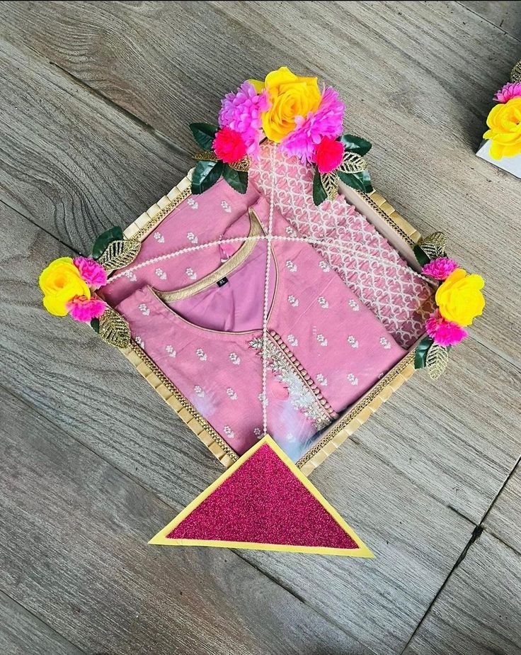 a pink and yellow cloth with flowers on it sitting on a wooden floor next to other items