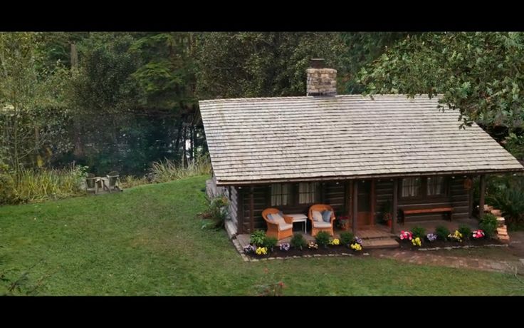 a small log cabin sitting on top of a lush green field