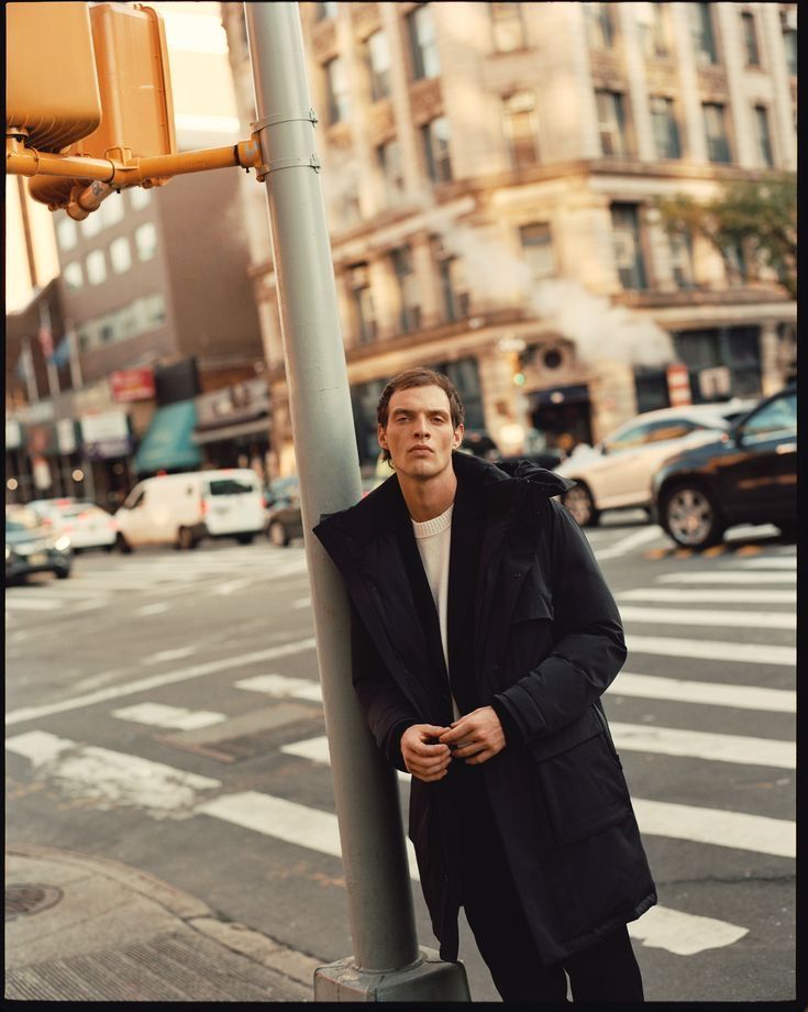 a man leaning against a pole on the street